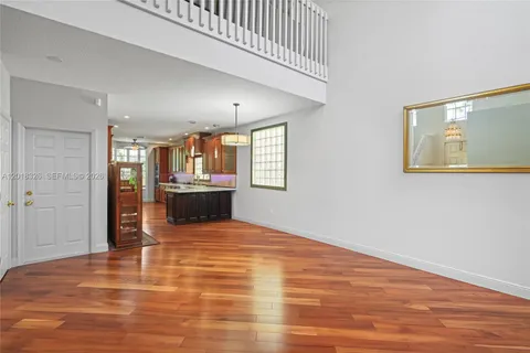 a view of a kitchen with kitchen island a sink wooden floor and a living room
