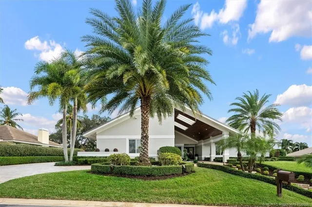 a view of a house with a yard and palm trees