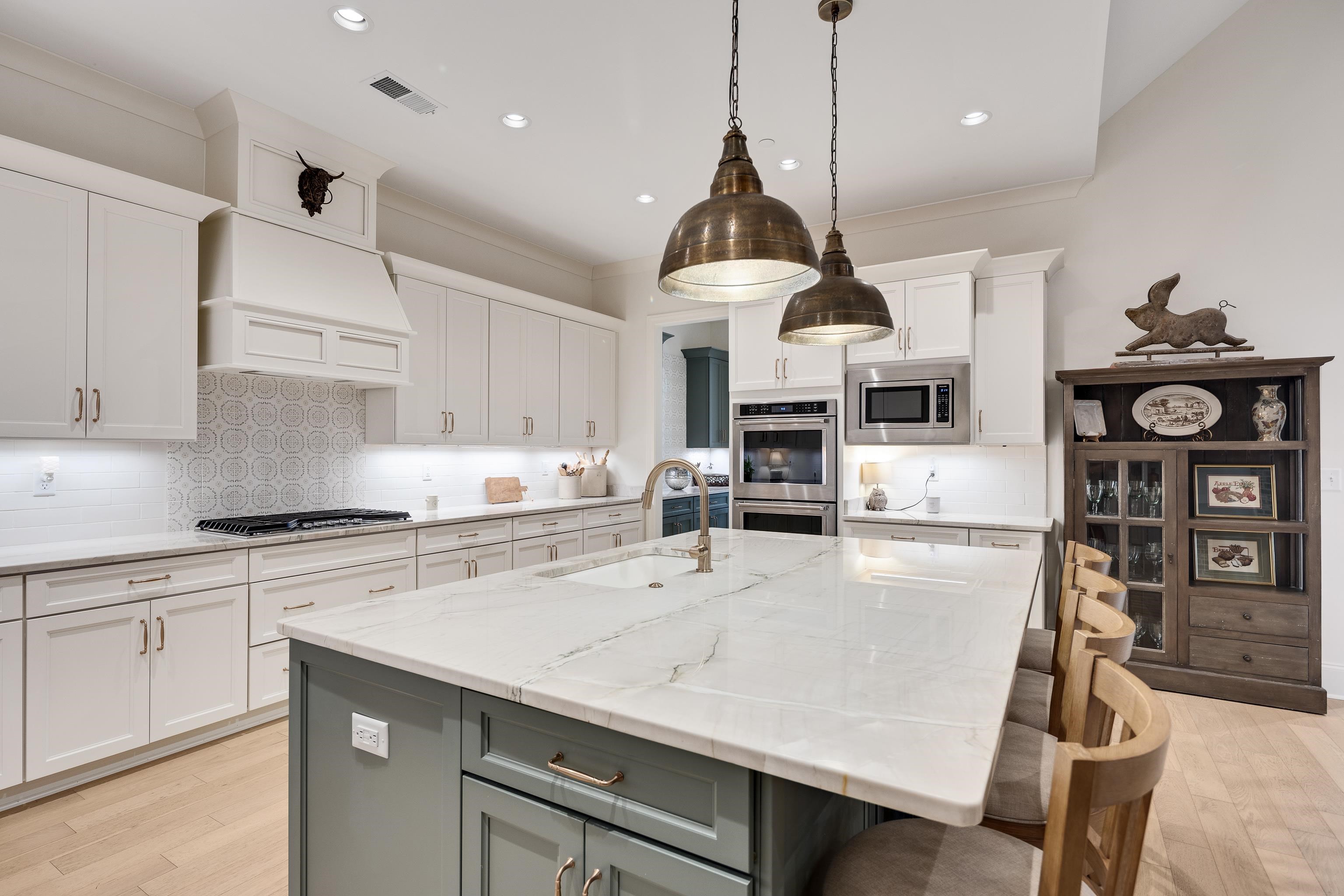 a kitchen with stainless steel appliances a stove a sink a kitchen island with chairs and white cabinets