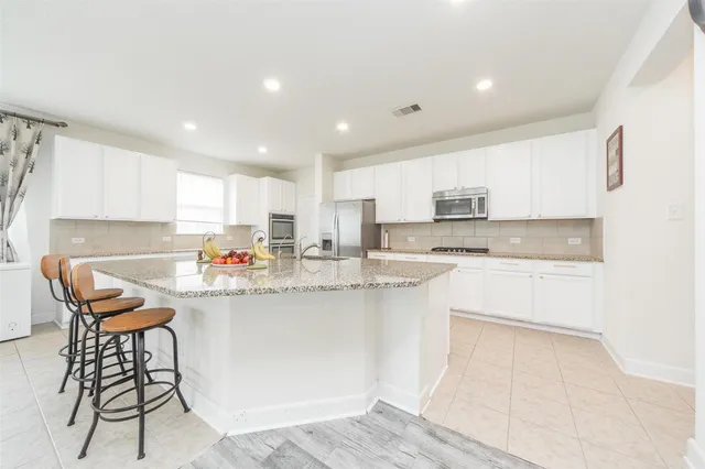 a kitchen with stainless steel appliances granite countertop a sink a stove a microwave a dining table and chairs