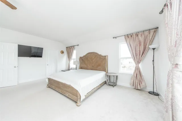 a spacious bedroom with a bed and a flat screen tv