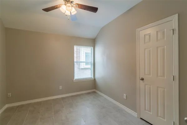 an empty room with a chandelier fan and windows