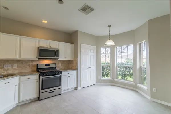 a kitchen with stainless steel appliances granite countertop a stove a sink and a microwave