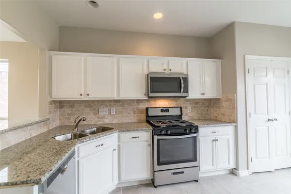 a kitchen with granite countertop white cabinets and stainless steel appliances