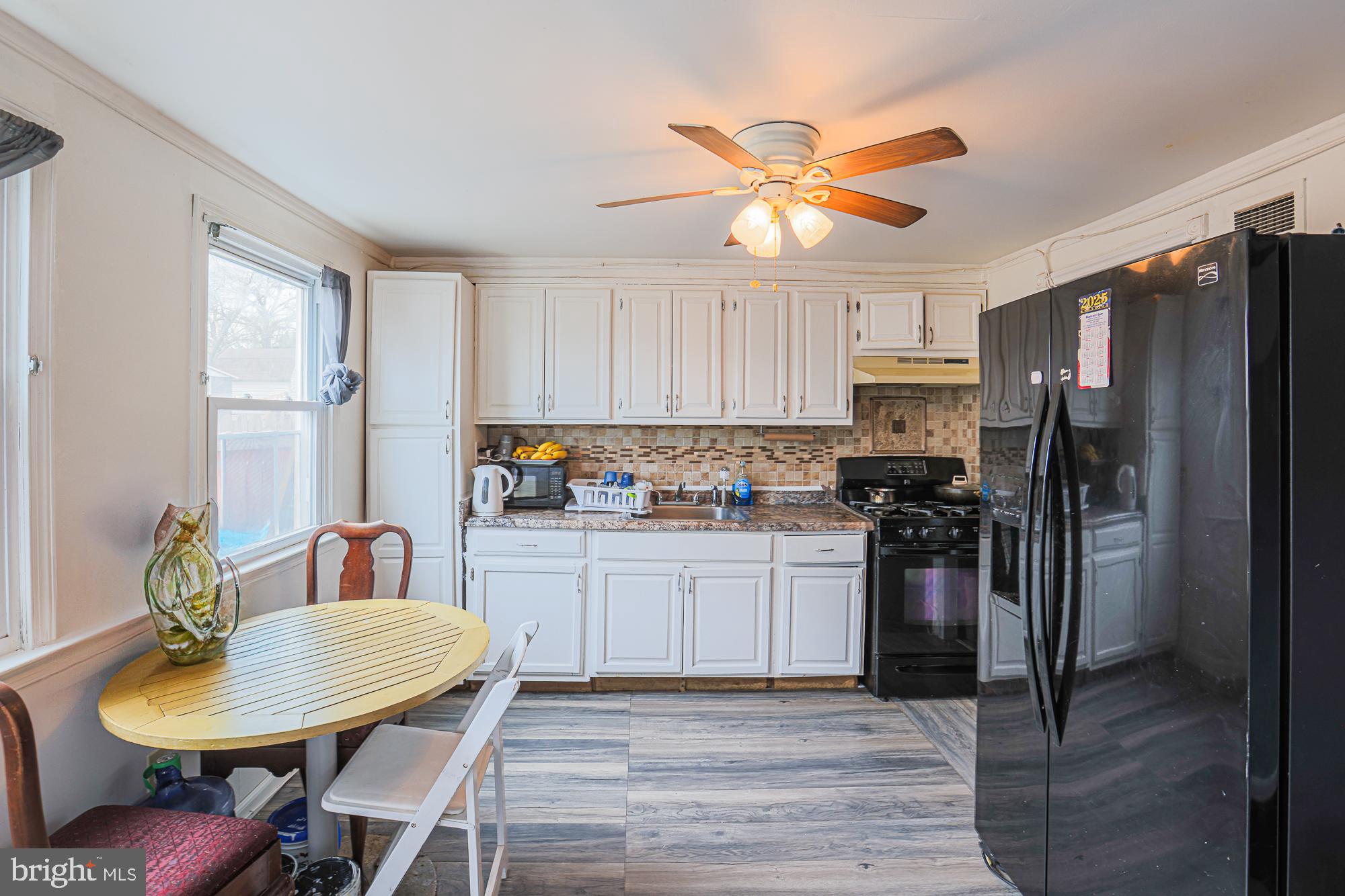 2707 Norfen Road Baltimore, MD 21227 - Photo 2 of 11 a kitchen with stainless steel appliances granite countertop a sink a stove a refrigerator cabinets a dining table and chairs