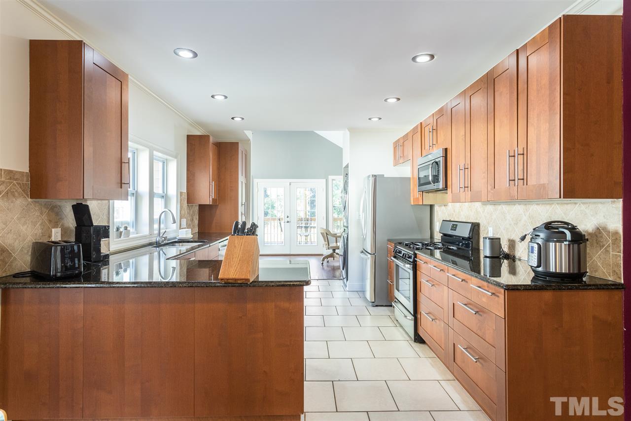 505 Holden Street Raleigh, NC 27604 - Photo 3 of 21 a kitchen with stainless steel appliances granite countertop a refrigerator a sink dishwasher a stove top oven a dining table and chairs with wooden floor