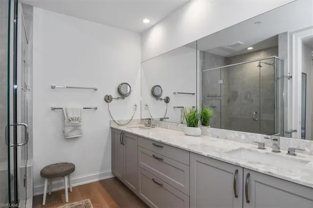 a bathroom with double vanity sinks a mirror and glass door shower