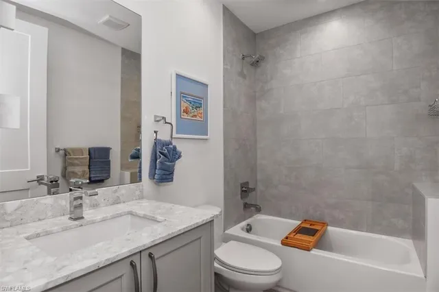 a bathroom with a granite countertop bathtub shower sink vanity mirror and toilet