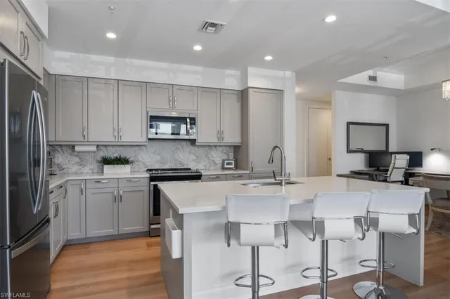a kitchen with kitchen island granite countertop a table chairs sink and cabinets