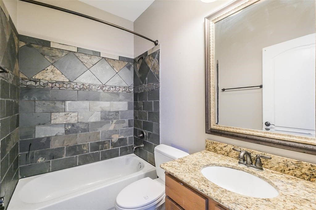 706 Allston Street, Unit B Houston, TX 77007 - Photo 21 of 33 a bathroom with a granite countertop bathtub sink vanity mirror and toilet