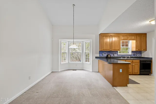 an empty room with chandelier fan and windows
