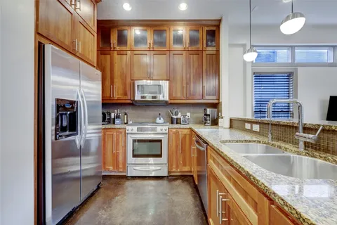 a kitchen with stainless steel appliances granite countertop a sink a stove and a refrigerator