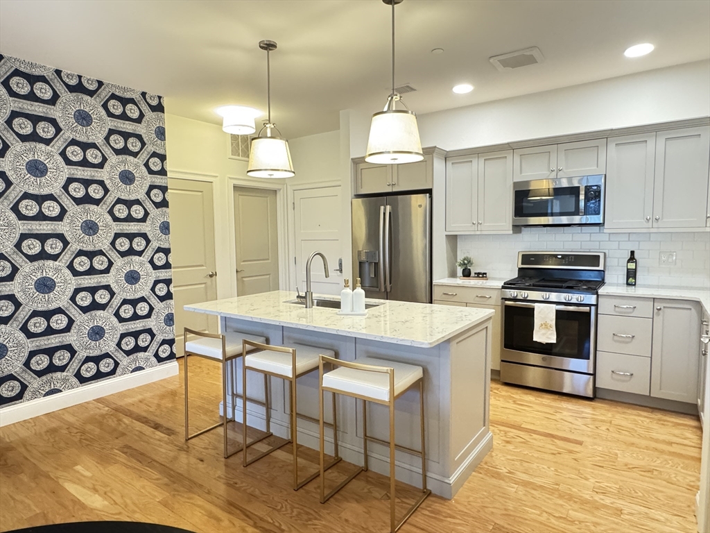 1 Revolution Way, Unit 307 Canton, MA 02021 - Photo 2 of 31 a kitchen with stainless steel appliances granite countertop a sink a stove a refrigerator and island
