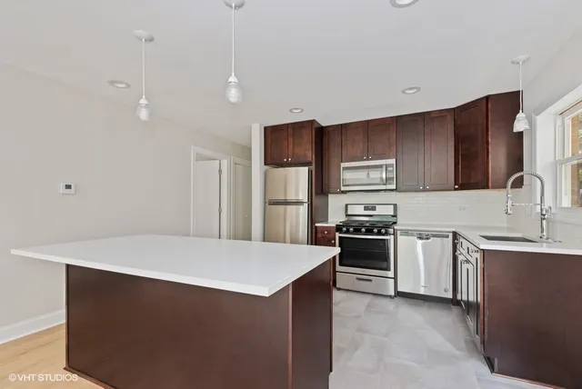 a kitchen with stainless steel appliances granite countertop a refrigerator a stove a sink and a microwave