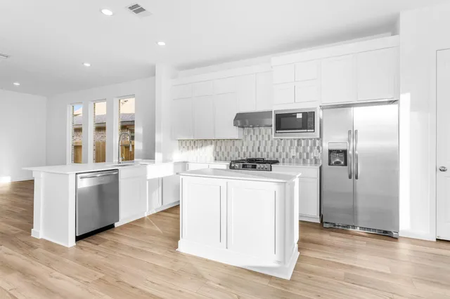 a kitchen with a refrigerator stove and wooden floor