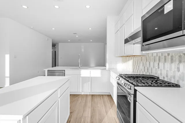 a kitchen with a sink and a stove top oven with wooden floor