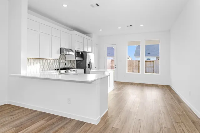 a kitchen with stainless steel appliances granite countertop a stove a sink and a refrigerator with wooden floors