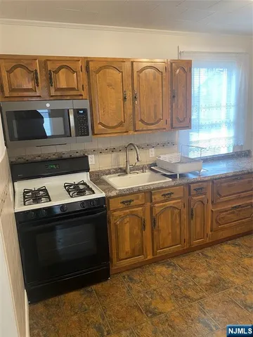 a kitchen with granite countertop a stove sink and cabinets