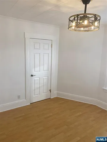 a view of an empty room with chandelier fan