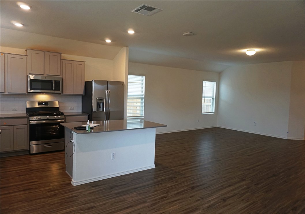 3493 Pauling Loop Round Rock, TX 78665 - Photo 3 of 19 a kitchen with granite countertop a refrigerator and a stove top oven