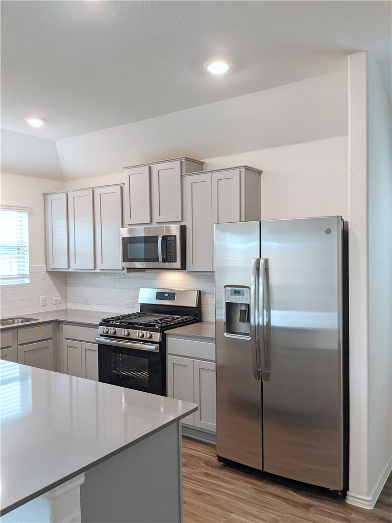 3493 Pauling Loop Round Rock, TX 78665 - Photo 6 of 19 a kitchen with granite countertop a refrigerator stove and microwave