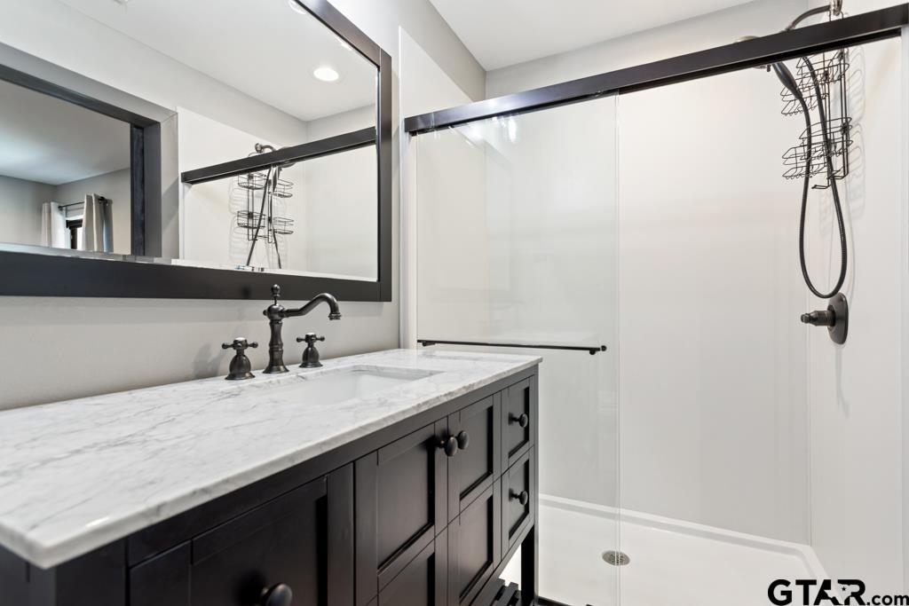 24116 Sun Ridge Road Lindale, TX 75771 - Photo 34 of 47 a bathroom with a granite countertop sink a mirror and a bathtub
