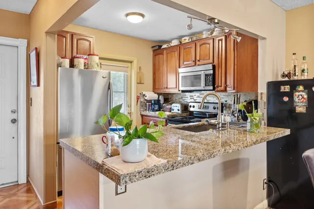 a kitchen with granite countertop a sink stove and refrigerator