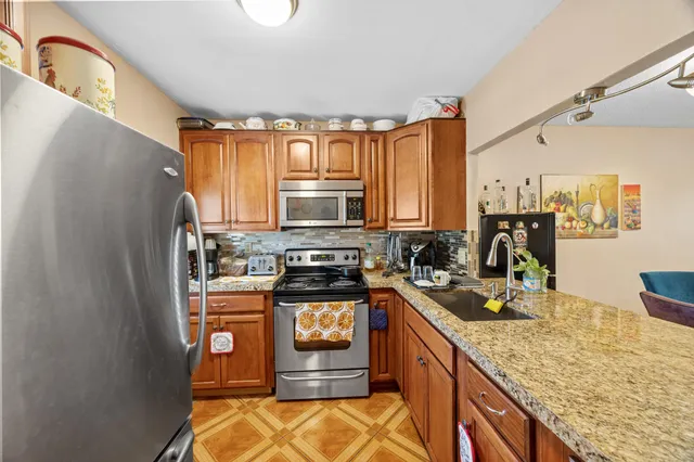 a kitchen with stainless steel appliances granite countertop a stove a sink and a refrigerator