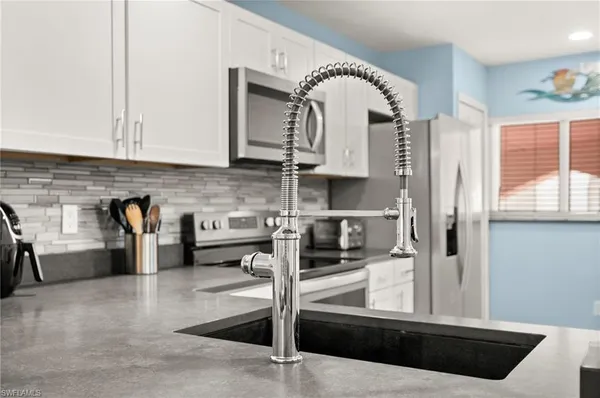 a view of kitchen with stainless steel appliances wooden floor and window