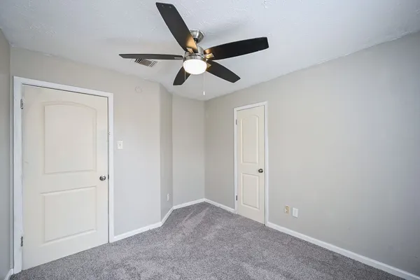 a view of an empty room with window and a ceiling fan