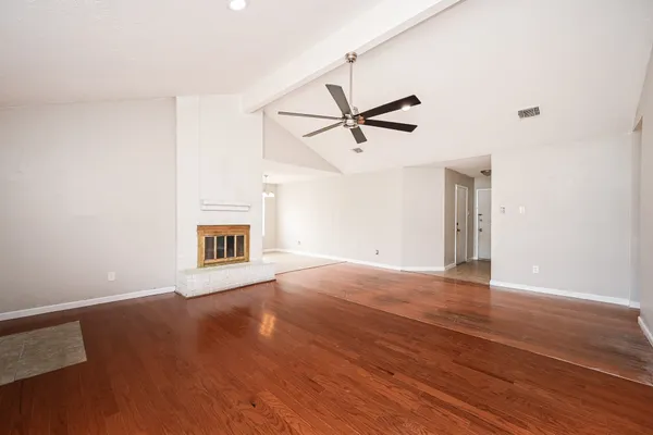 a view of an empty room with a window and wooden floor
