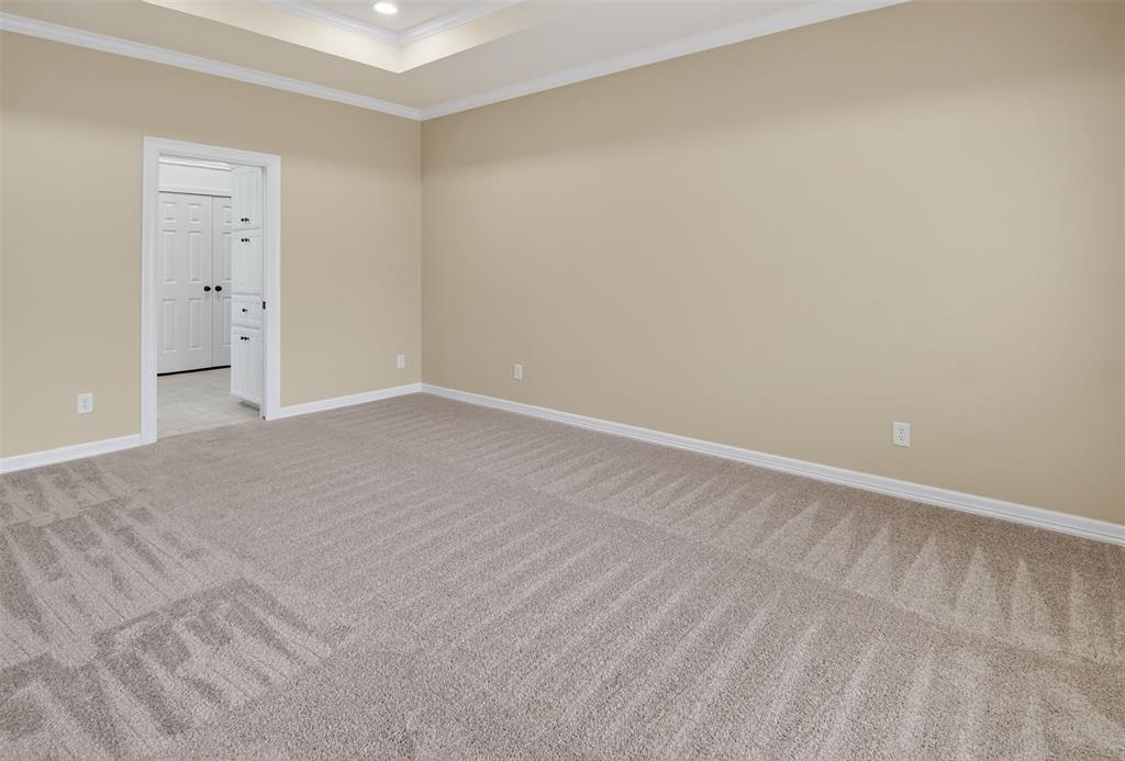 2122 Clear Lake Road Weatherford, TX 76087 - Photo 22 of 40 Spacious primary bedroom with en suite bath, tray ceiling detail, can lights, and ceiling fan.