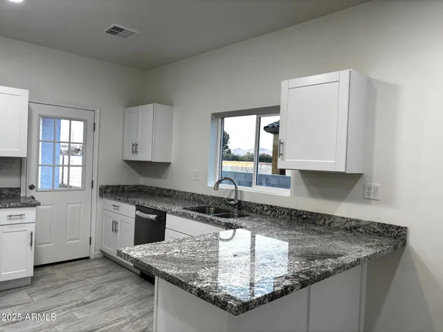 a kitchen with kitchen island granite countertop a sink a stove and cabinets