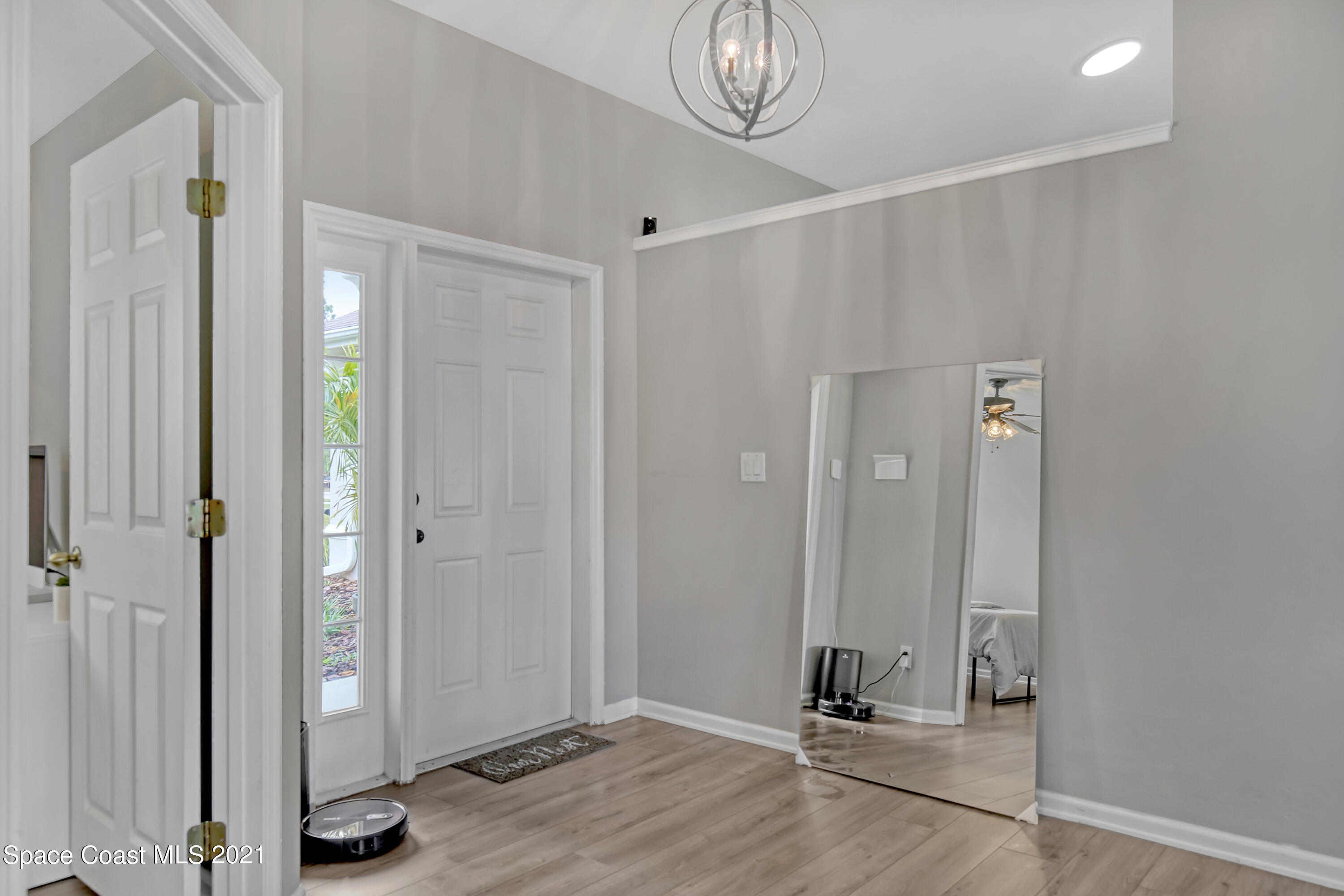 1277 Harlingen Road Southwest Palm Bay, FL 32908 - Photo 3 of 32 a view of a hallway with wooden floor and a mirror