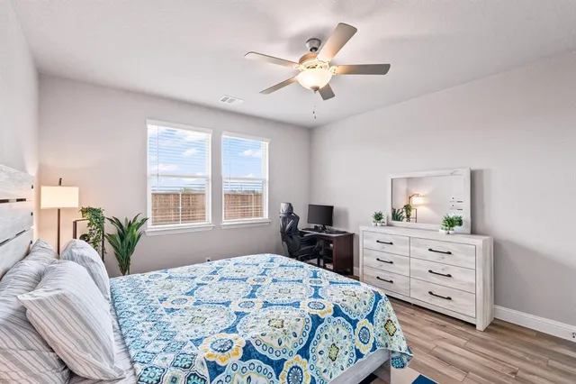 a bedroom with a bed and a dresser with wooden floor