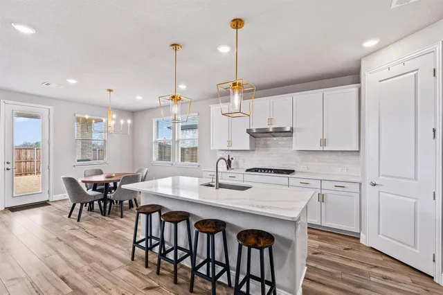 a kitchen with stainless steel appliances granite countertop a kitchen island hardwood floor sink stove dining table and chairs