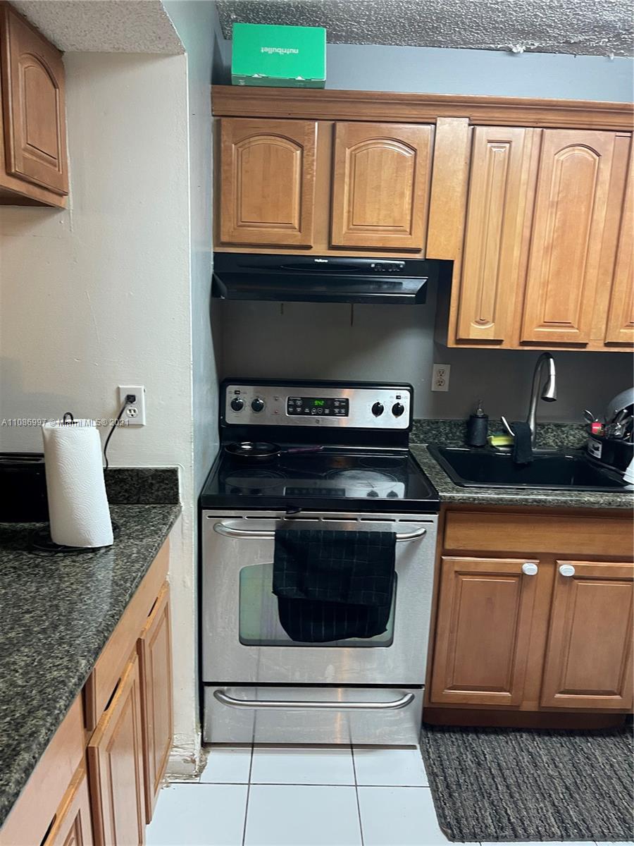 20681 Northeast 4th Place, Unit 101 Miami, FL 33179 - Photo 3 of 5 a kitchen with granite countertop a stove and a sink