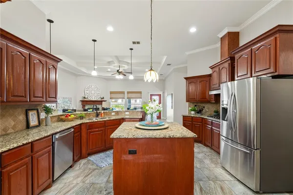 a kitchen with kitchen island granite countertop a sink refrigerator and cabinets