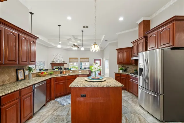 a kitchen with kitchen island granite countertop a sink refrigerator and cabinets
