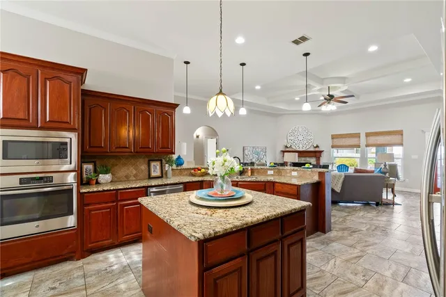 a kitchen with kitchen island granite countertop wooden cabinets and stainless steel appliances