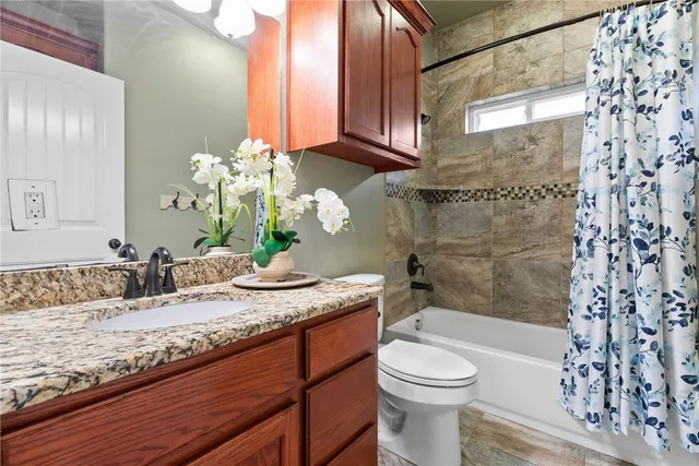 a bathroom with a granite countertop sink a toilet and shower