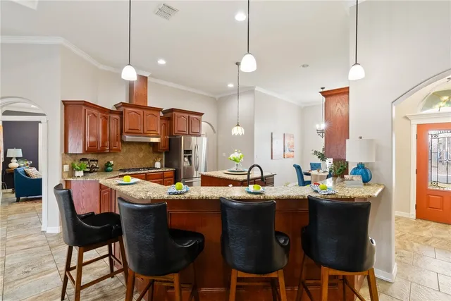a kitchen with stainless steel appliances kitchen island granite countertop a sink a stove a dining table and chairs