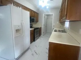 a kitchen with granite countertop a refrigerator stove and sink
