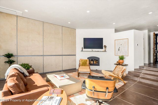 a living room with furniture a flat screen tv and a floor to ceiling window