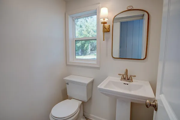 a bathroom with a toilet a sink and mirror