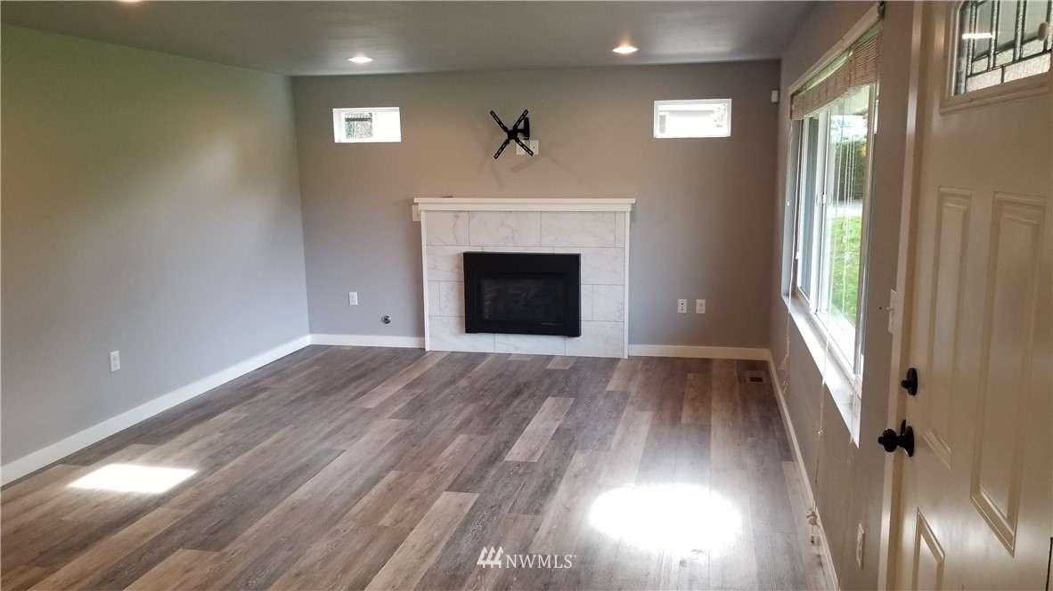 7531 Lower Ridge Road Everett, WA 98203 - Photo 3 of 25 a view of empty room with wooden floor fireplace and window