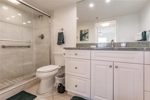 a bathroom with a granite countertop toilet a sink and a mirror