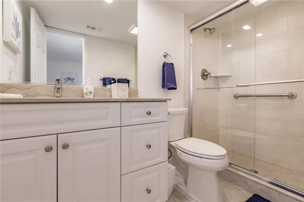 a bathroom with a granite countertop sink a toilet a mirror and shower
