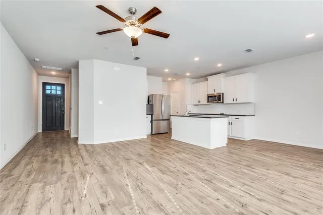 a view of kitchen with kitchen island wooden floor center island and stainless steel appliances