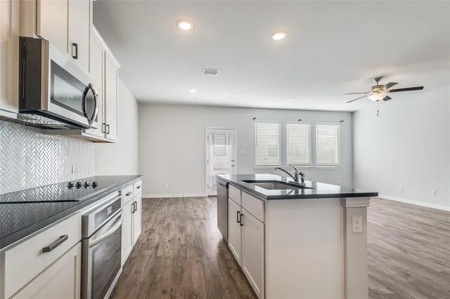 a kitchen with stainless steel appliances granite countertop a sink a stove and a wooden floors